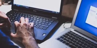 Person Typing On Two Laptops Resized Esm H200